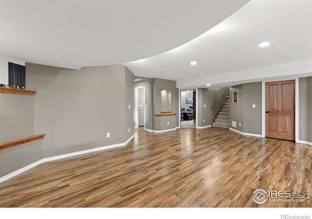 1046 Greens Pl, Erie, CO 80516 - unfurnished living room featuring light wood-style flooring, stairs, baseboards, recessed lighting, and arched walkways