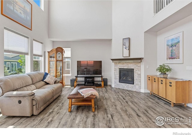 1863 Pioneer Cir, Lafayette, CO 80026 - living area featuring a high ceiling, wood finished floors, a stone fireplace, and baseboards