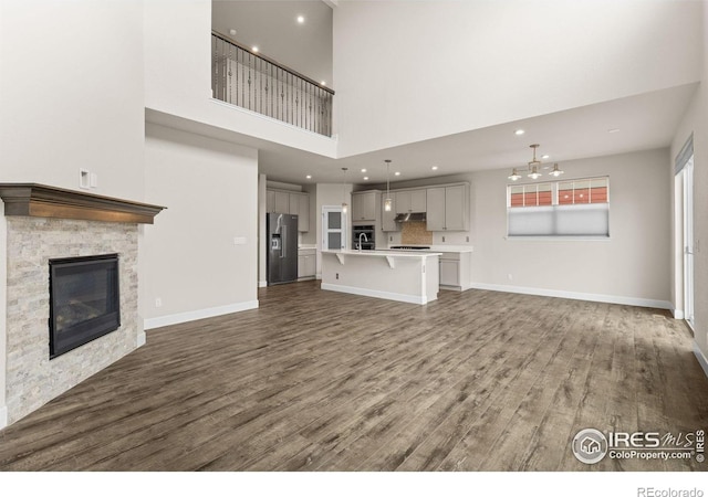 1863 Pioneer Cir, Lafayette, CO 80026 - unfurnished living room featuring wood finished floors, a towering ceiling, a fireplace, a chandelier, and recessed lighting