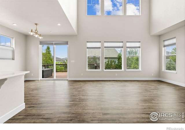 1863 Pioneer Cir, Lafayette, CO 80026 - unfurnished living room featuring dark wood-style floors, a chandelier, a high ceiling, and recessed lighting
