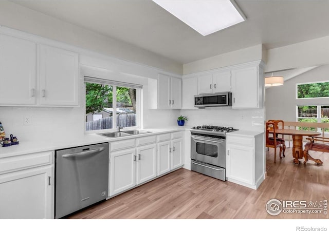 8940 W 80th Dr, Arvada, CO 80005 - kitchen with appliances with stainless steel finishes, backsplash, white cabinets, and light wood finished floors