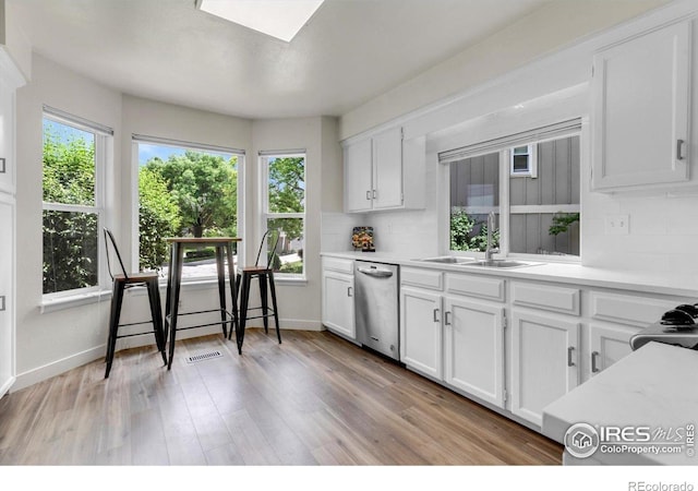 8940 W 80th Dr, Arvada, CO 80005 - kitchen featuring dishwasher, light countertops, white cabinets, and light wood finished floors