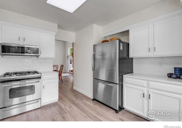 8940 W 80th Dr, Arvada, CO 80005 - kitchen featuring stainless steel appliances, light wood finished floors, white cabinets, light countertops, and backsplash