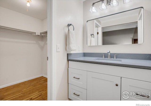 8940 W 80th Dr, Arvada, CO 80005 - bathroom featuring vanity, wood finished floors, and a walk in closet