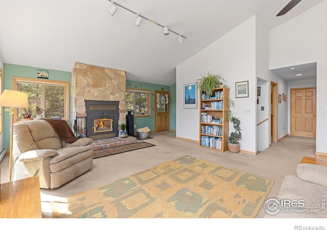 317 W 5th St, Nederland, CO 80466 - living area featuring rail lighting, carpet floors, baseboards, a stone fireplace, and ceiling fan