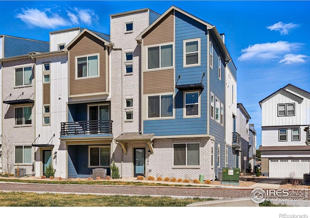 townhome / multi-family property featuring brick siding, cooling unit, and board and batten siding