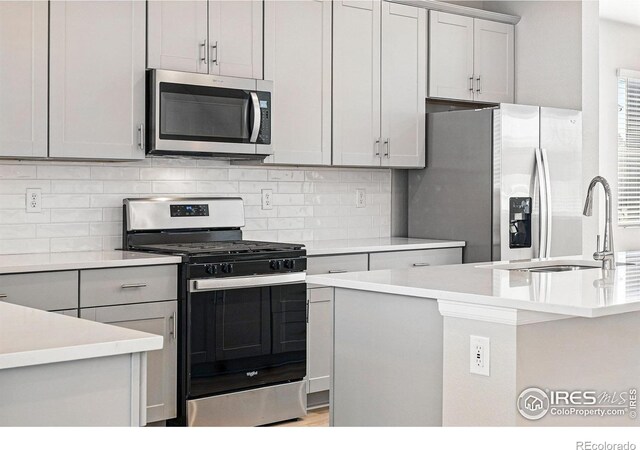 kitchen featuring light countertops, a sink, stainless steel appliances, and decorative backsplash