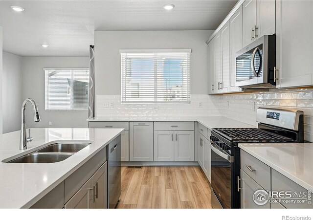 kitchen with light countertops, a sink, gray cabinets, and appliances with stainless steel finishes