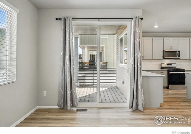 interior space featuring light countertops, backsplash, light wood-style floors, visible vents, and appliances with stainless steel finishes