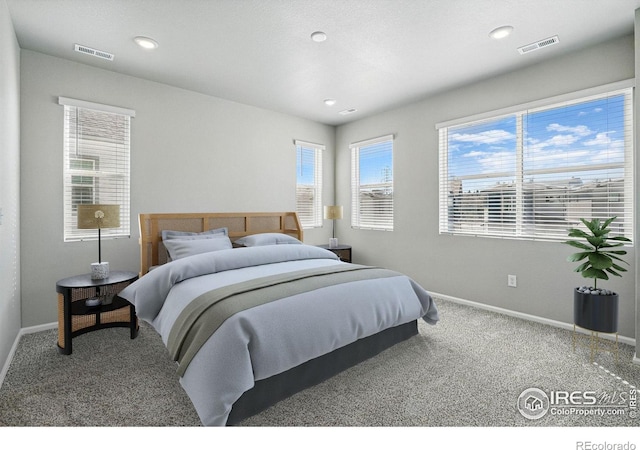 carpeted bedroom featuring baseboards, visible vents, and multiple windows