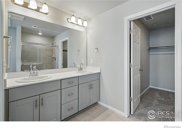 bathroom featuring double vanity, a sink, a stall shower, and visible vents