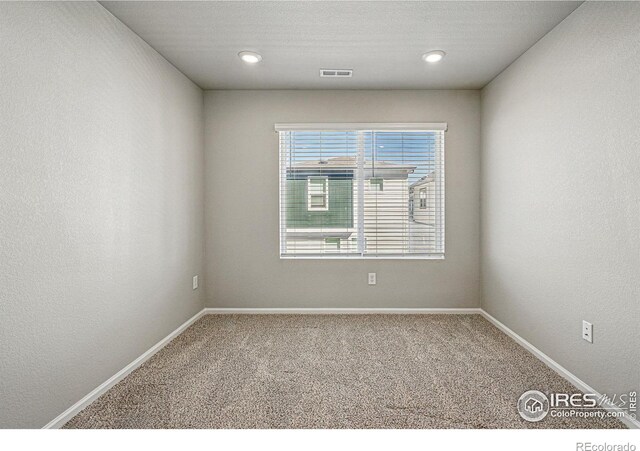carpeted empty room featuring baseboards and visible vents