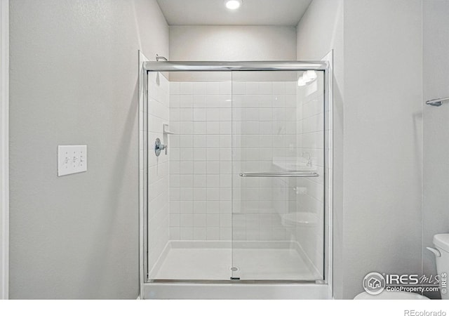 bathroom featuring toilet and a shower stall
