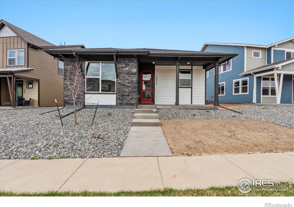 2273 Peregrine Dr, Brighton, CO 80601 - view of front of home featuring roof with shingles, stone siding, and covered porch