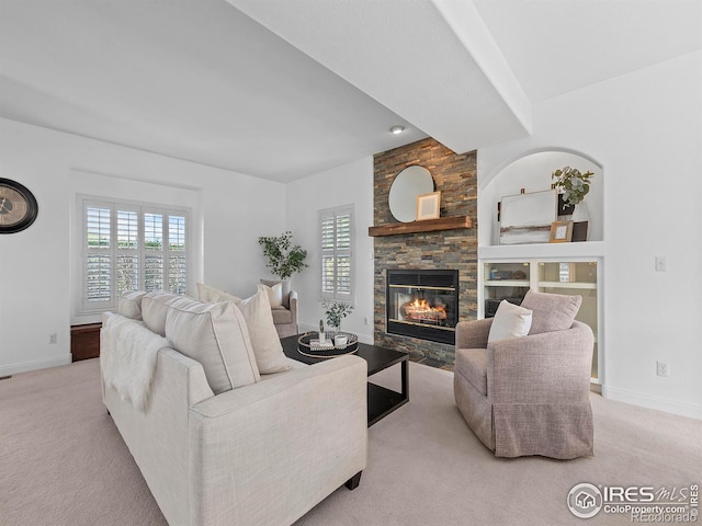 living room with carpet flooring, a stone fireplace, baseboards, and a wealth of natural light