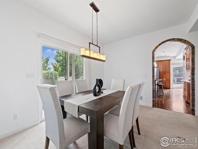 dining space featuring arched walkways, baseboards, and carpet
