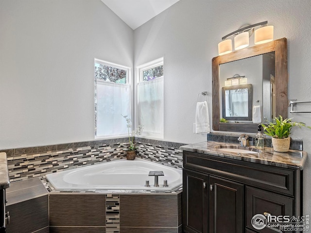 bathroom with vanity, lofted ceiling, and a garden tub