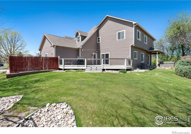 rear view of property featuring a lawn, cooling unit, a deck, and fence