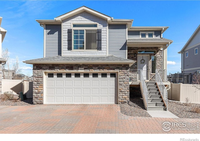 3536 Valleywood Ct, Johnstown, CO 80534 - view of front of home featuring stairway, fence, an attached garage, stone siding, and decorative driveway