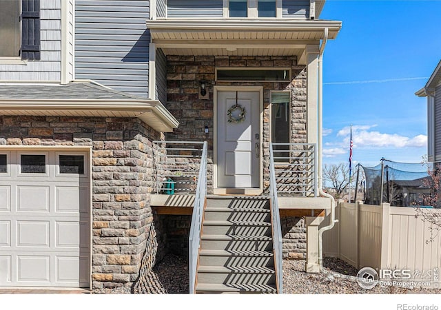 3536 Valleywood Ct, Johnstown, CO 80534 - view of exterior entry featuring stone siding, an attached garage, and fence