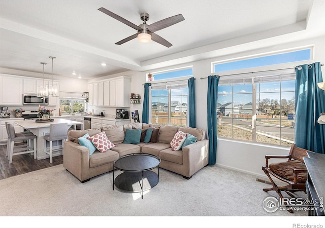 3536 Valleywood Ct, Johnstown, CO 80534 - living area with a raised ceiling, ceiling fan with notable chandelier, and a wealth of natural light