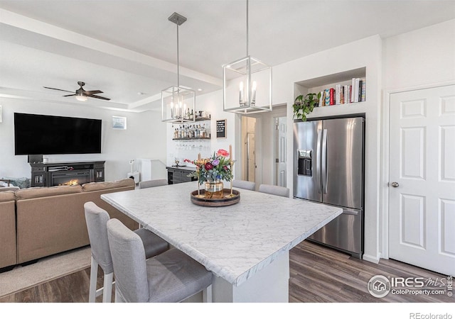 3536 Valleywood Ct, Johnstown, CO 80534 - kitchen featuring a breakfast bar, dark wood-style floors, stainless steel fridge, and light countertops