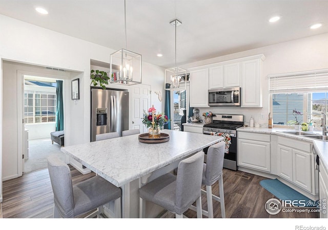 3536 Valleywood Ct, Johnstown, CO 80534 - kitchen featuring a sink, a breakfast bar area, appliances with stainless steel finishes, dark wood finished floors, and white cabinets