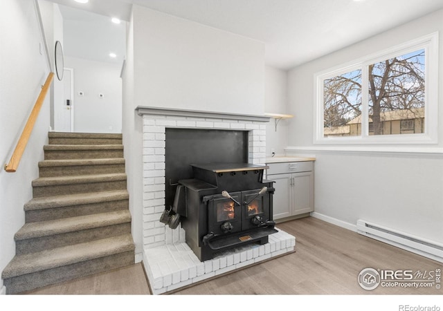 2836 Adobe Dr, Fort Collins, CO 80525 - interior space featuring a baseboard heating unit, recessed lighting, a wood stove, baseboards, and wood finished floors