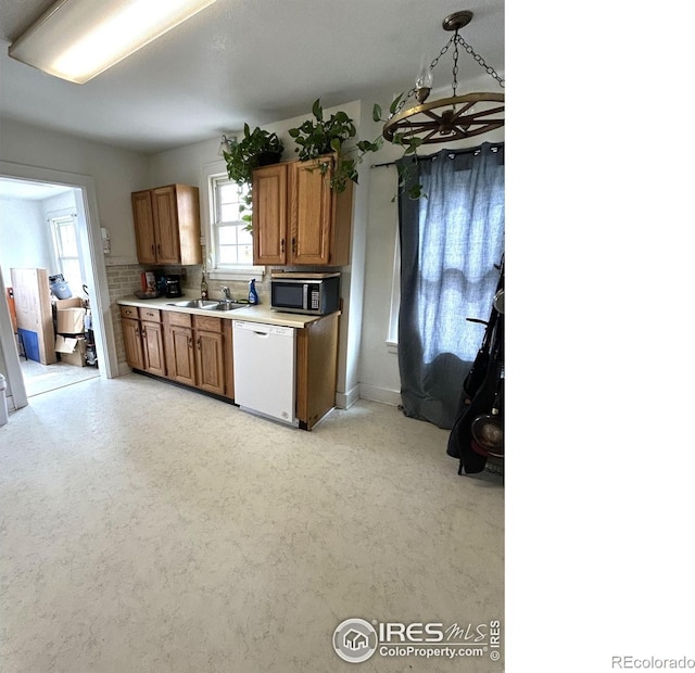730 Lake St, Fort Morgan, CO 80701 - kitchen featuring light countertops, a sink, brown cabinets, white dishwasher, and stainless steel microwave