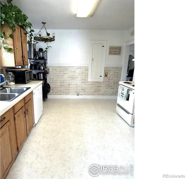 730 Lake St, Fort Morgan, CO 80701 - kitchen featuring a wainscoted wall, light countertops, white appliances, a sink, and brown cabinetry
