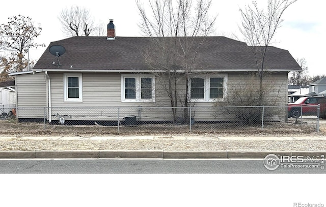 730 Lake St, Fort Morgan, CO 80701 - view of side of property with a chimney, a fenced front yard, and a shingled roof