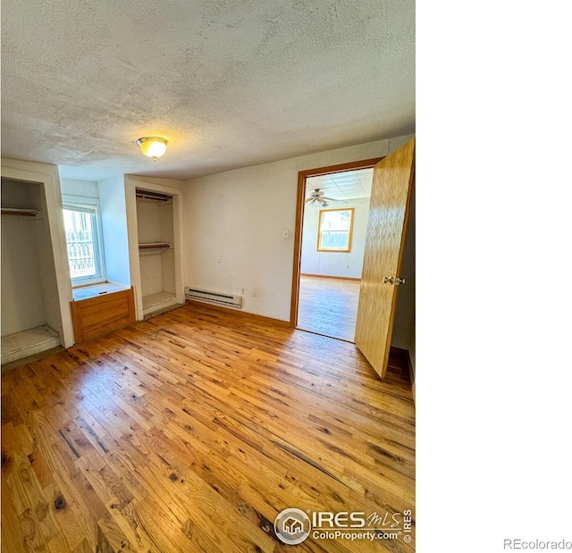 3828 Mckinley Ave, Wellington, CO 80549 - unfurnished bedroom featuring a textured ceiling, a baseboard heating unit, and light wood-type flooring