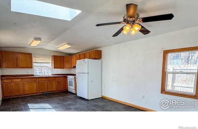 3828 Mckinley Ave, Wellington, CO 80549 - kitchen featuring white appliances, lofted ceiling with skylight, baseboards, a sink, and brown cabinets