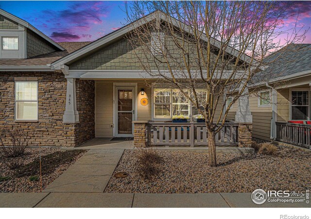 view of front of home featuring stone siding and a porch