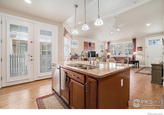 kitchen featuring light wood-style flooring, ceiling fan, brown cabinets, a sink, and hanging light fixtures