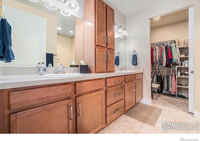 bathroom with double vanity, a sink, tile patterned floors, and a spacious closet