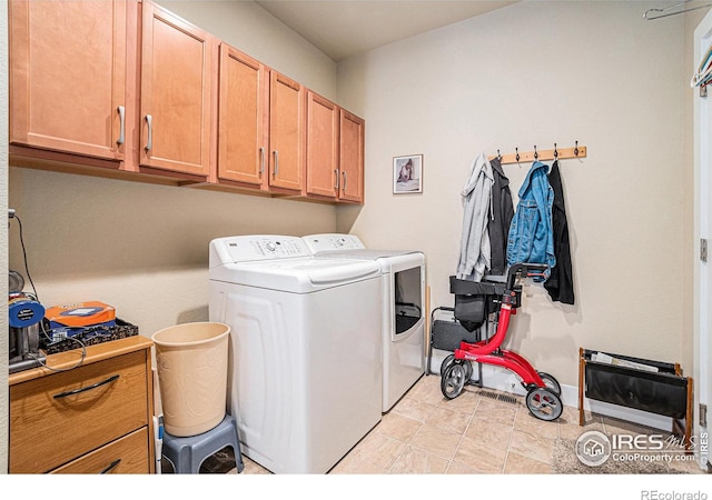 clothes washing area featuring baseboards, cabinet space, and separate washer and dryer