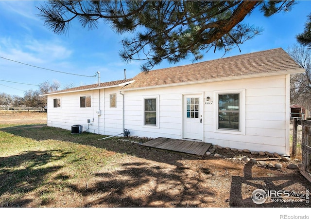 view of front of home with fence, a front lawn, central AC unit, and roof with shingles