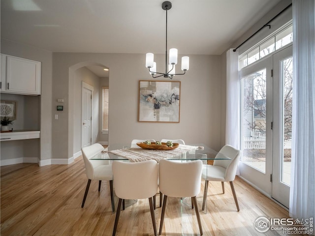 2946 Shoshone Trl, Lafayette, CO 80026 - dining space with light wood-style floors, arched walkways, a chandelier, and a wealth of natural light