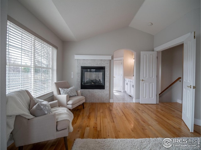2946 Shoshone Trl, Lafayette, CO 80026 - sitting room with arched walkways, vaulted ceiling, a tile fireplace, light wood finished floors, and an upstairs landing