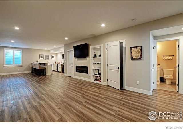 27857 Hopi Trl, Loveland, CO 80534 - unfurnished living room with recessed lighting, wet bar, wood finished floors, and baseboards