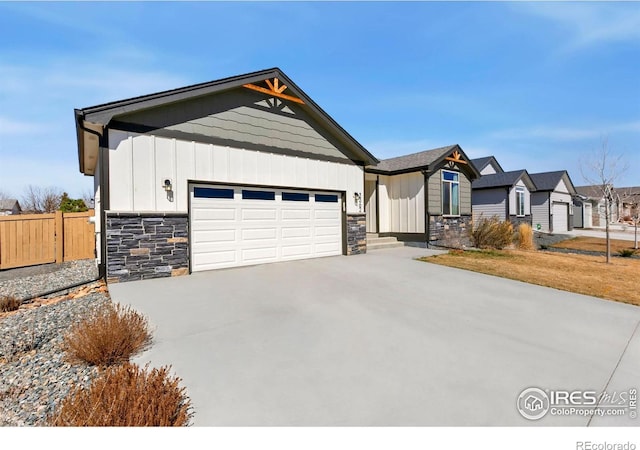 3362 Buffalo Grass Ln, Wellington, CO 80549 - view of front of home featuring stone siding, board and batten siding, an attached garage, fence, and concrete driveway