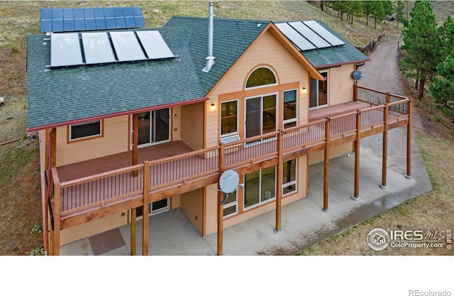 10435 Roan Mountain Rd, Loveland, CO 80538 - back of house featuring a wooden deck, solar panels, a shingled roof, and a patio area