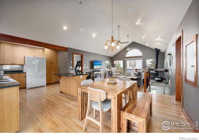 10435 Roan Mountain Rd, Loveland, CO 80538 - dining space with high vaulted ceiling, light wood-style flooring, a wood stove, and a notable chandelier