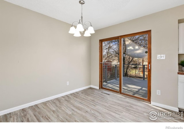 unfurnished dining area with an inviting chandelier, visible vents, baseboards, and light wood-type flooring