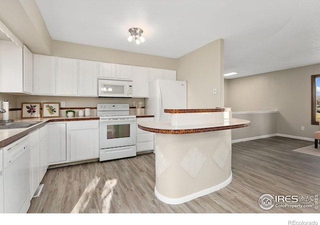 kitchen with white appliances, white cabinetry, light wood-style floors, and a sink