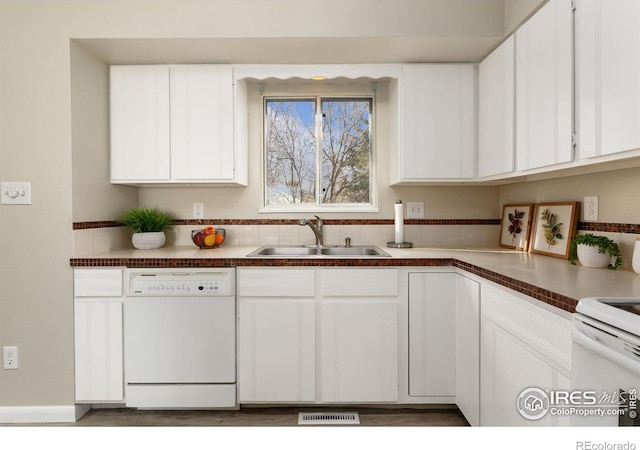kitchen featuring visible vents, white cabinets, a sink, and white appliances
