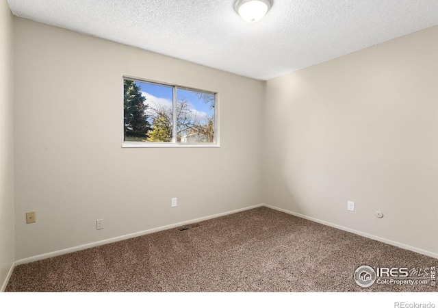 spare room featuring carpet, baseboards, and a textured ceiling