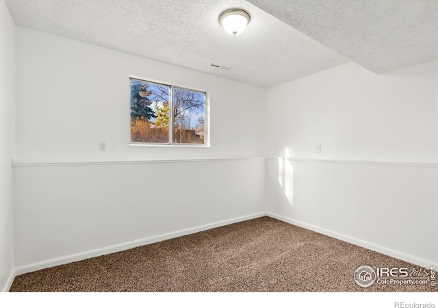 carpeted empty room featuring visible vents, baseboards, and a textured ceiling