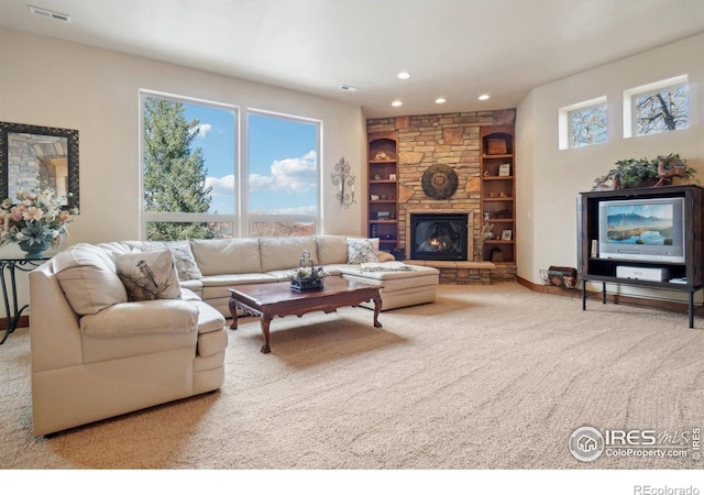 living room featuring carpet floors, visible vents, a stone fireplace, built in shelves, and recessed lighting